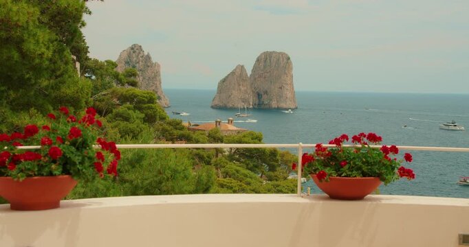 Flowers in pots on terrace overlooking Faraglioni rock formations in Capri Italy