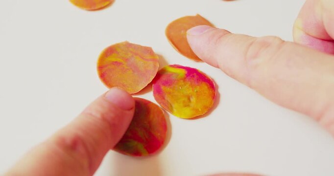 Designer arranging abstract pattern from hardened plastic pieces on a surface before transferring it, first-person top view, close-up.