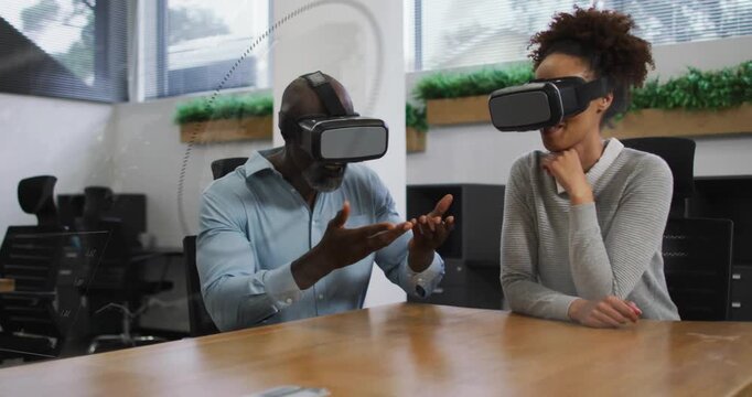 Group strapping VR headsets at meeting table and pointing and resizing model for business design