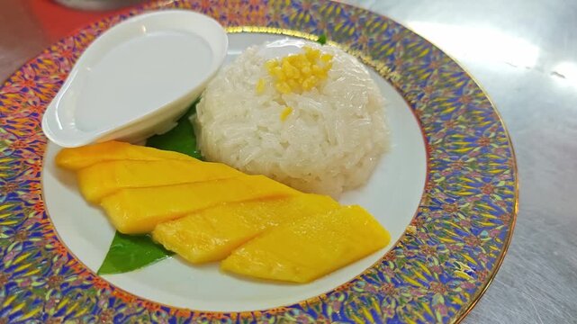 Exquisite Thai Mango Sticky Rice with beautifully carved mango in leaf shape and coconut cream in a heart-shaped bowl.