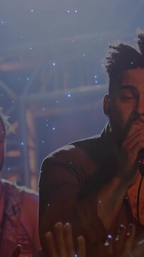 Vertical video: Male singer holding mic singing at concert comets drifting over face engaging crowd