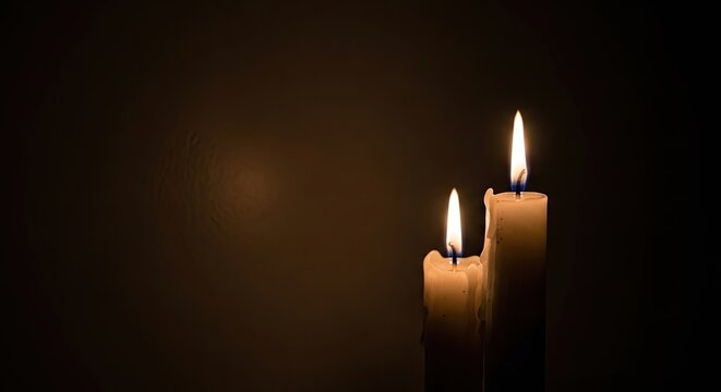 Three lit candles in a dark room with warm glow and soft shadows