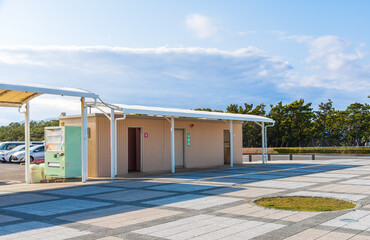 Naklejka premium Public rest area in japan featuring a clean restroom building and vending machine at a parking lot. concept of public infrastructure, travel convenience, urban facility and highway services.
