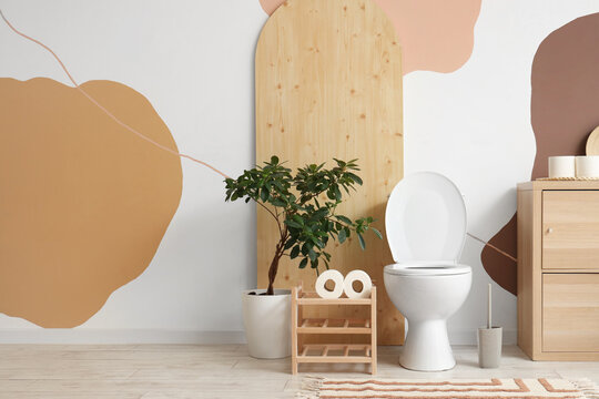 Interior of restroom with toilet bowl, stand and plant