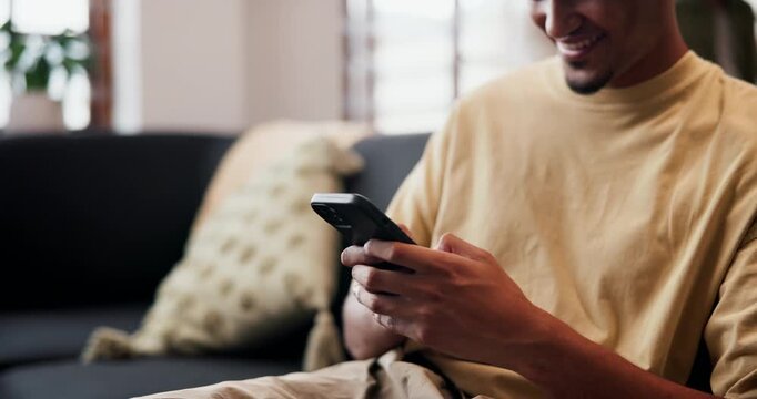 Hands, phone and texting on sofa in home with smile, web chat or online dating in living room. Happy man, smartphone and typing on mobile app, laugh and meme with post on social network at house