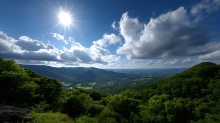 Fototapeta premium Panoramic view from a lush green mountain peak with a bright sun shining through dramatic clouds over a sprawling valley below