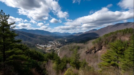 Fototapeta premium Expansive scenic panorama of a mountain valley town under a bright blue sky with scattered clouds