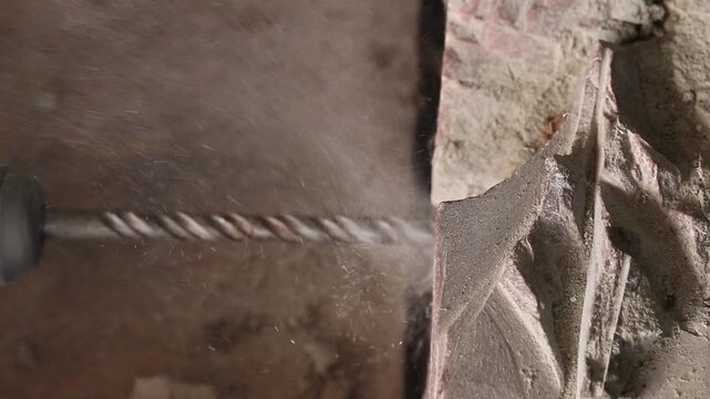 The process of drilling a hole with a concrete drill inserted into a perforator. Creating a hole in concrete or stone. The process of construction or repair. Close-up of the process of drilling a hole