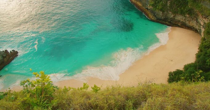 Panoramic view of hidden tropical beach with turquoise ocean water and cliffs