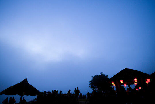 Silhouette of a group of people sitting under the umbrella in the evening