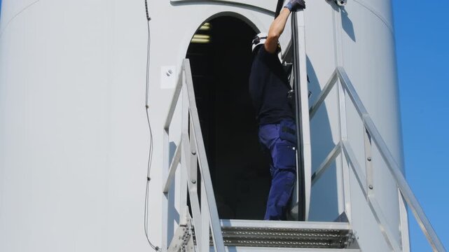 Technician installs rubber gasket to hatch at windmill service ground slow motion. Engineer replaces obsolete seal on metal door at wind turbine