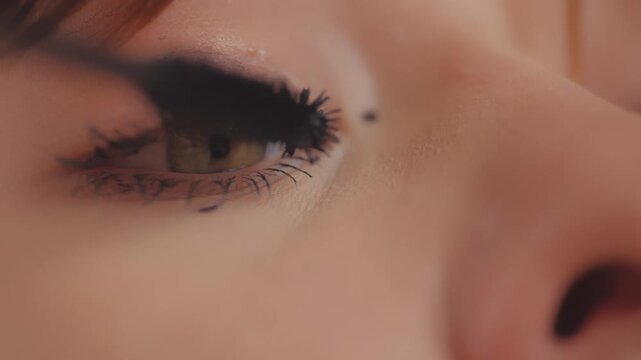 Woman applying black mascara on her eyelashes