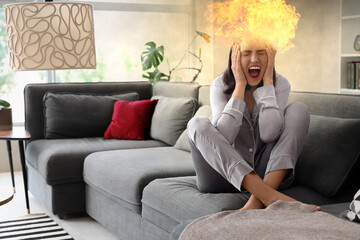 Obraz premium Beautiful young afraid woman sitting on sofa and screaming in living room