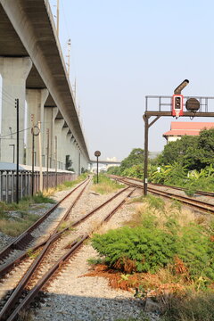 Modern elevated railway line crosses over old train tracks with a signal light