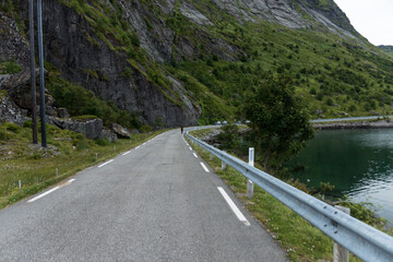 Obraz premium Narrow Mountain Road Beside Lake and Steep Rocky Cliffs