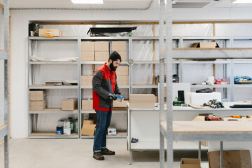 Fototapeta premium Worker packing cardboard box in warehouse for shipping