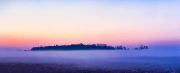 Panorama krajobraz rano z  kolorowym niebem i mgłą na łąkach pod lasem © KoLesfot