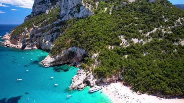 Cala Sisine Beach Sardinia Drone Video, Top Down Turquoise Sea with Tourist Boat, Aerial View Tilting Up to Massive Limestone Cliffs, Wild Nature Coastline of Orosei Gulf No People, 4K Travel Movie