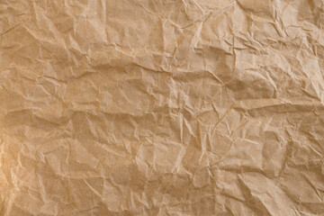 Fototapeta premium Crumpled Brown Kraft Paper Texture Background,Macro,Close-up top view of a wrinkled and crumpled brown kraft paper sheet. This textured background features organic creases, folds, and shadows, perfect