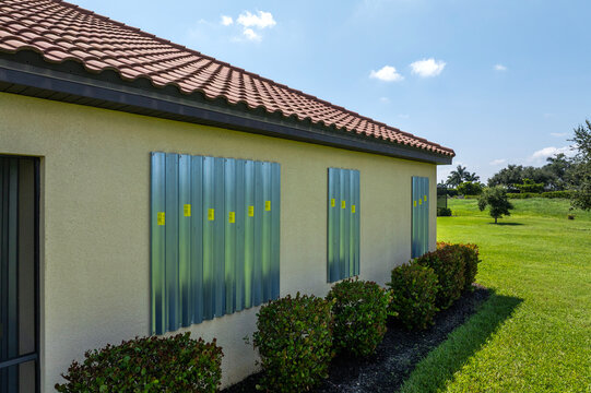 Boarded up windows with steel storm shutters for hurricane protection of residential house. Protective measures before natural disaster in Florida