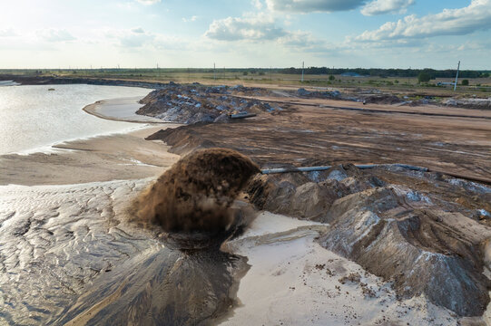 Industrial pipe spraying mixture of water and sediment at mining area, part of phosphate extraction operation in Florida.