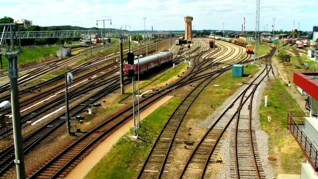 Railway tracks and train station infrastructure on a sunny day with clouds