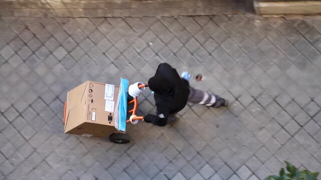 Repartidor transportista con carretilla y paquete de entrega de pedido a domicilio