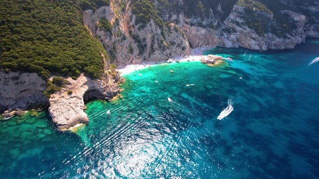 Cala Mariolu Sardinia Drone Video, Top Down Turquoise Water with Motorboats, Aerial Reveal of Massive Limestone Cliff over Pebble Beach, Orosei Gulf Tourist Boat 4K Cinematic Italy best beaches