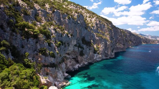 Cala Sisine Sardinia Drone Video, Flying Close to Wild Limestone Cliffs, Aerial Transition to Coastline with Motorboats, Orosei Gulf Sea Travel, Rugged Nature and Summer Tourism Movement 4K