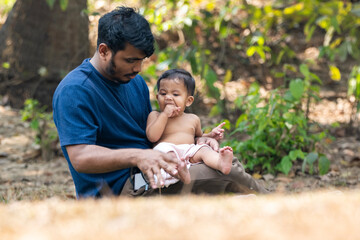 Fototapeta premium The man is engaging playfully with the baby in an outdoor environment