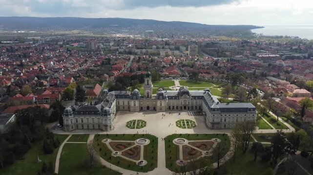 Aerial drone view grandeur of Festetics Palace in Keszthely, Hungary, surrounded by meticulously designed gardens and pathways. The baroque architecture, with its ornate facade.