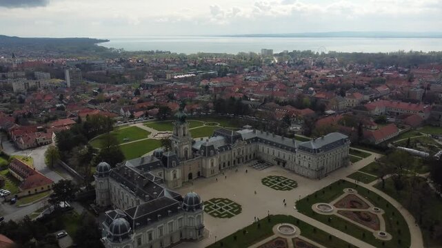 Aerial drone view grandeur of Festetics Palace in Keszthely, Hungary, surrounded by meticulously designed gardens and pathways. The baroque architecture, with its ornate facade.