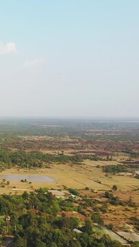 Wide aerial shot of rural fields, scattered trees, and a small pond in the Baray Occidental region under a clear sky. The landscape features agricultural plots and natural greenery.