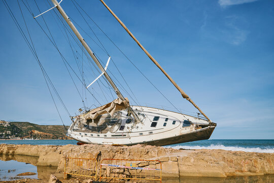Close up of damaged sailing yacht stranded on rocky shore
