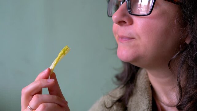 Woman Holding and Eating Single Fresh Romaine Lettuce Leaf Against Green Background &mdash; Lactuca sativa Cos Lettuce, Healthy Eating, Fresh Produce and Plant-Based Food Concept