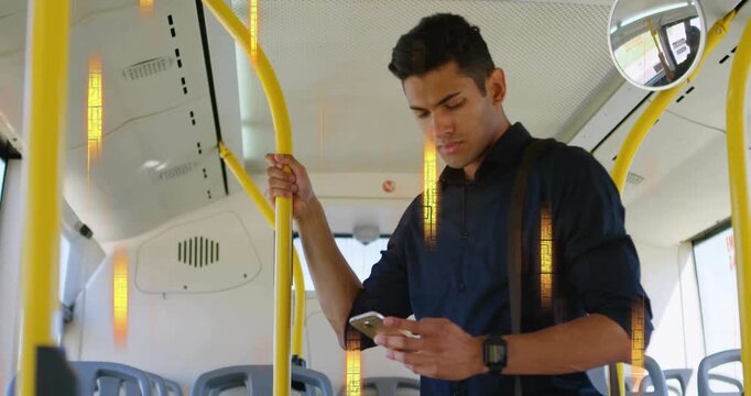 Holding yellow handrail and smartphone, commuter steadying on city bus, wearing navy shirt and bag