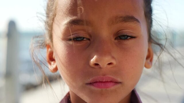 Face, child and sad outdoor with disappointment, wind and emotions of sorrow for childhood abandonment. Serious, young girl or lonely orphan with abuse trauma, poverty crisis and feelings of neglect.