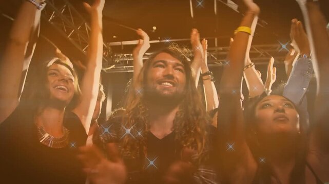 Performer starting music, front-row man and woman clapping, raising hands, star overlays flaring