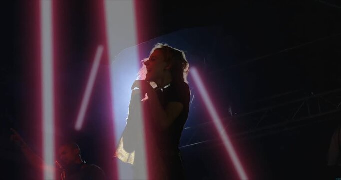 Vertical video: Leaning singer flipping hair into mic with halo pulsing on stage and magenta bars
