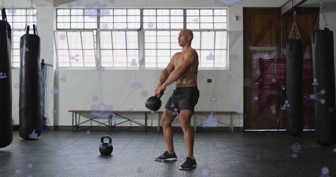 Trainer bending and gripping kettlebell, driving hips, swinging and pressing overhead for fitness