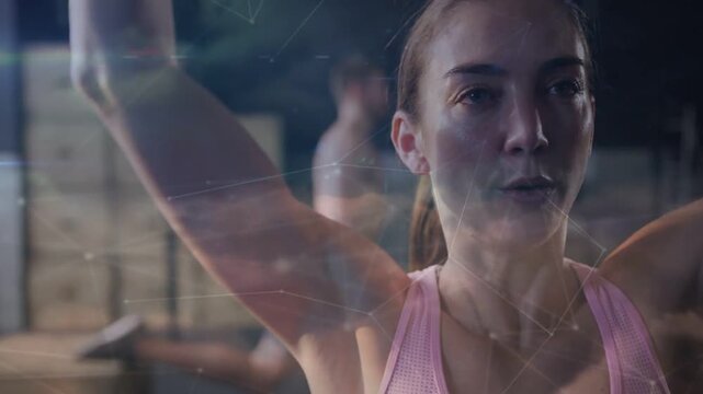 Holding hex dumbbell, woman training shoulders at gym in pink top, boxes, reflections for strength