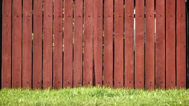 Red wooden fence creating a boundary in a green garden backyard
