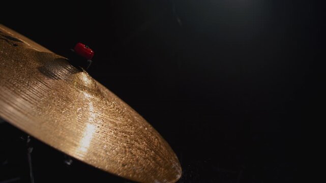 Water drops flying from drum kit. Drum player hits the cymbals of the drum set powerfully during the rock show on a stage under strobe flashes close up. Drummer playing the drums with drumsticks