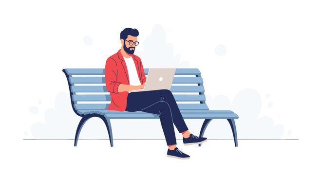 Young bearded man wearing glasses and a red jacket sitting on a park bench and working intently on his silver laptop for remote work concepts.