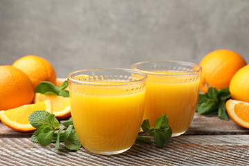 Citrus juice in glasses, fresh oranges and mint leaves on wooden table, closeup © New Africa