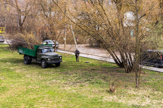 Workers Clearing Branches near an Old Truck in a Lviv Park