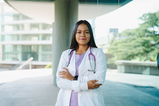 Confident Latin female doctor or nurse with stethoscope standing with arms crossed, portraying healthcare professionalism