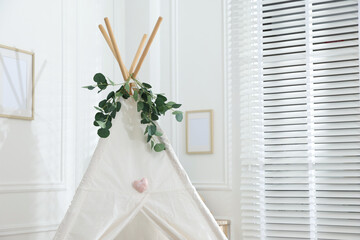 Toy wigwam with floral decor in room, closeup. Space for text © New Africa