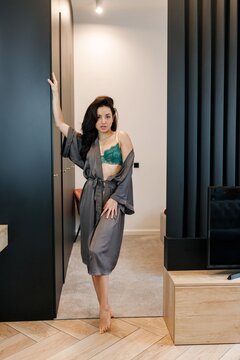 Sexy young woman wearing hot underwear with gray negligee while psoing in the room at home. Romantic, passion, lifestyle concept