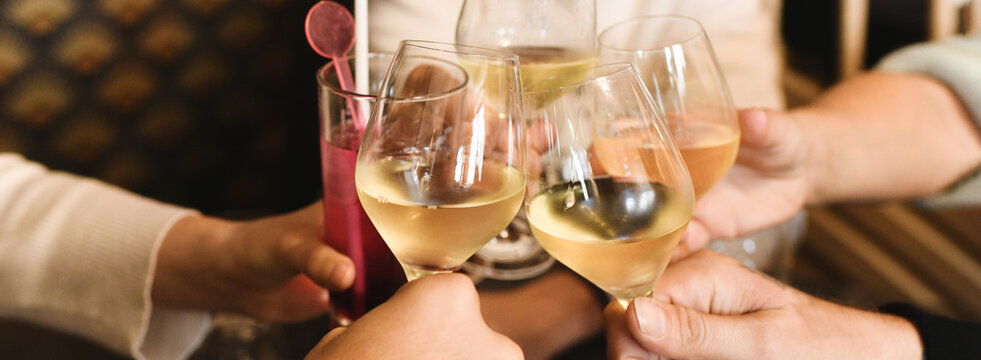 Clinking glasses with white wine and toasting.